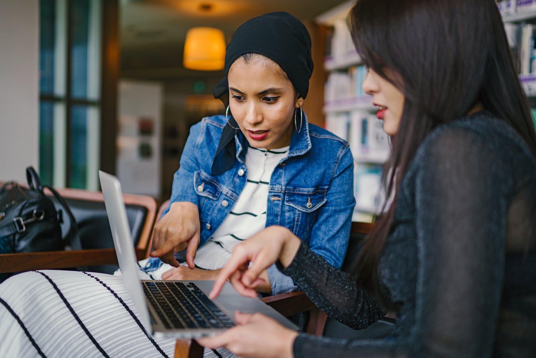 Two women meeting during business travel over a remote work laptop  Photo by mentatdgt on Pexels.com